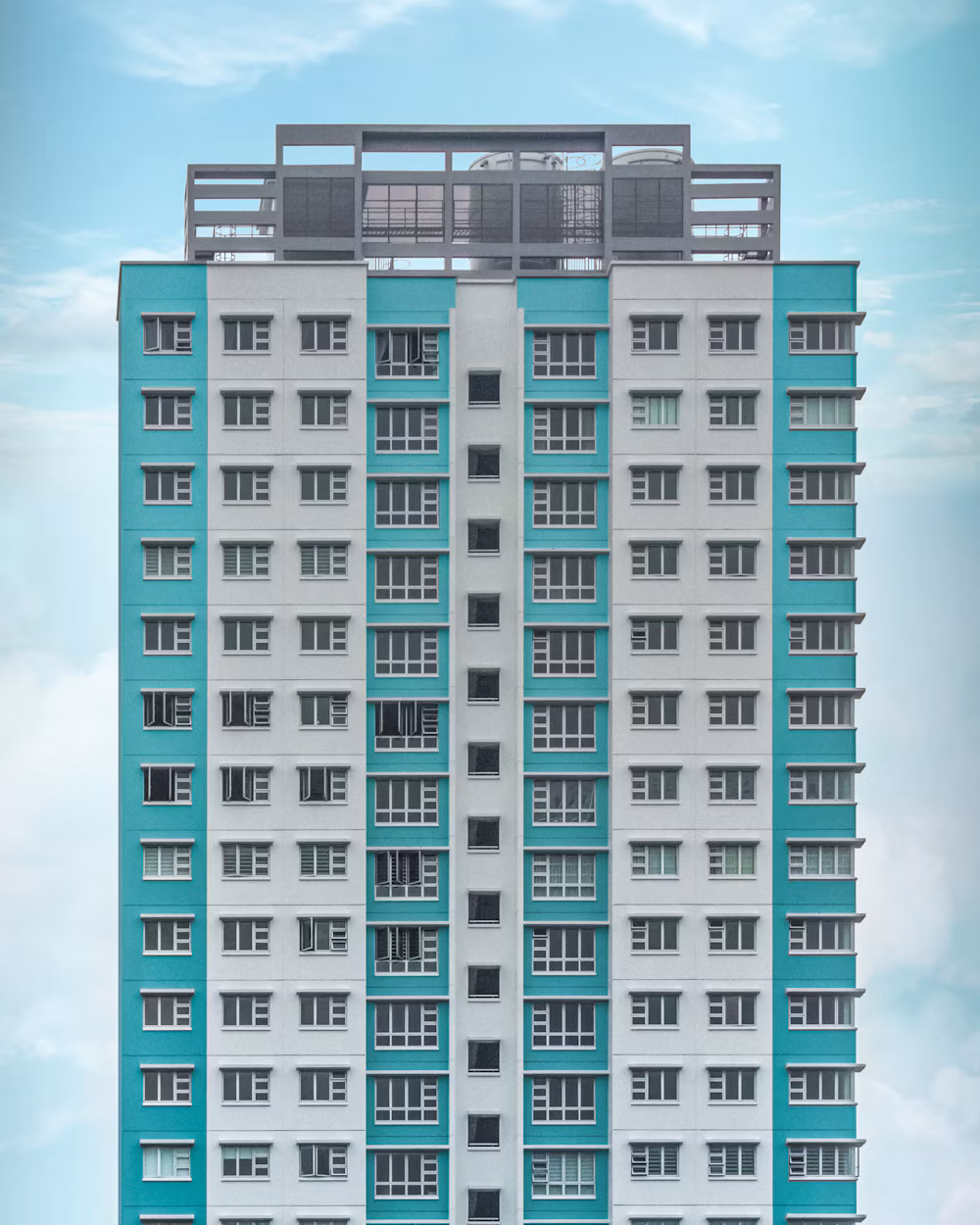 Teal and white residential high-rise rising into a clear sky